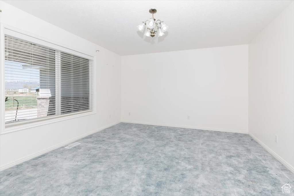 Spare room featuring carpet floors and a chandelier