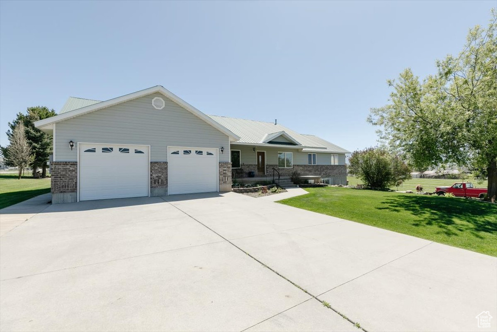 Ranch-style house featuring a front yard, a garage, and concrete driveway