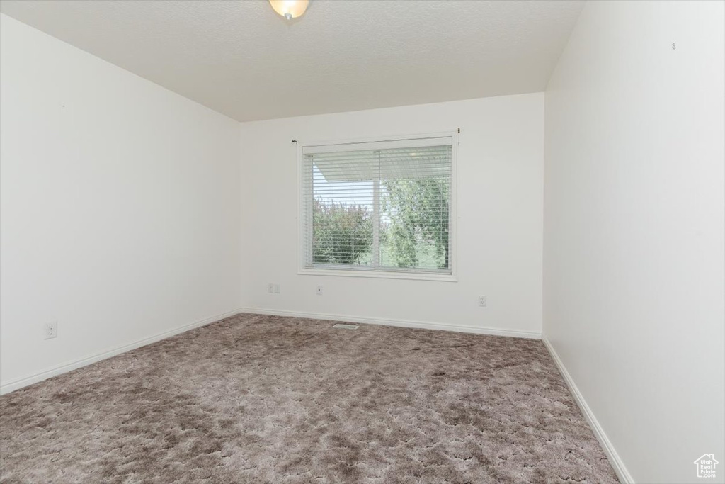 Carpeted empty room featuring baseboards