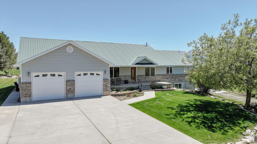 View of front of home featuring driveway, an attached garage, a front yard, and covered porch