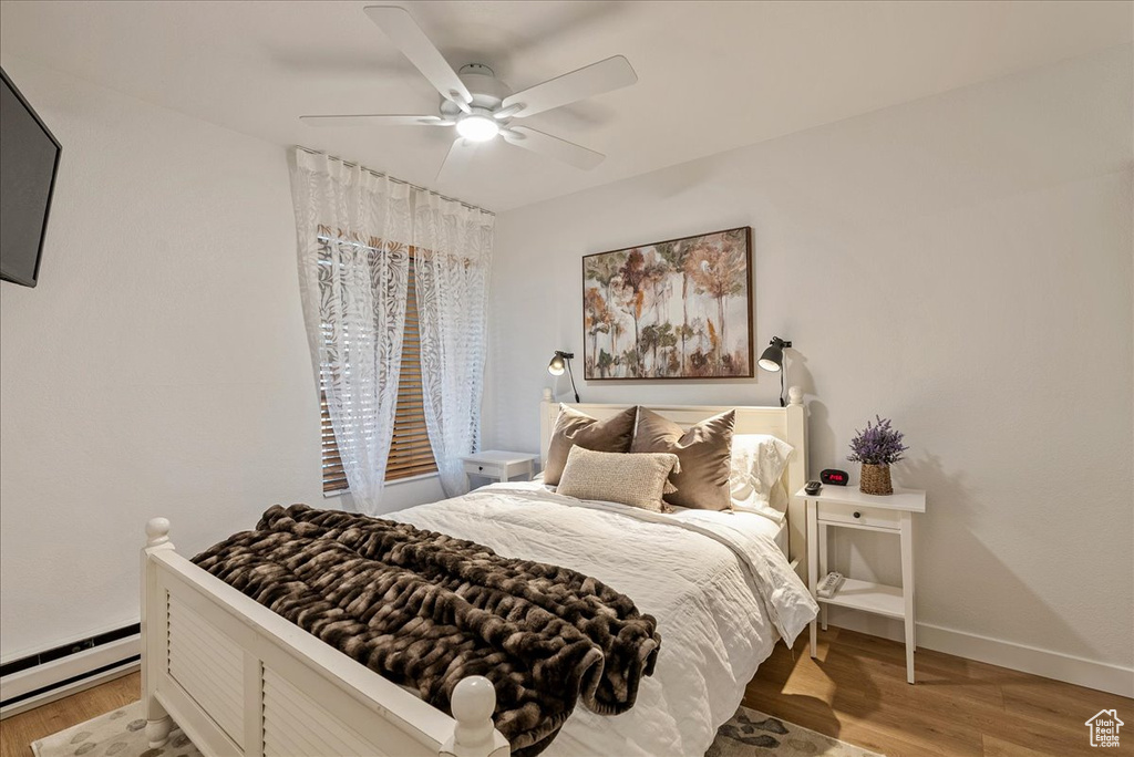 Bedroom with baseboards, light wood-style flooring, baseboard heating, and ceiling fan