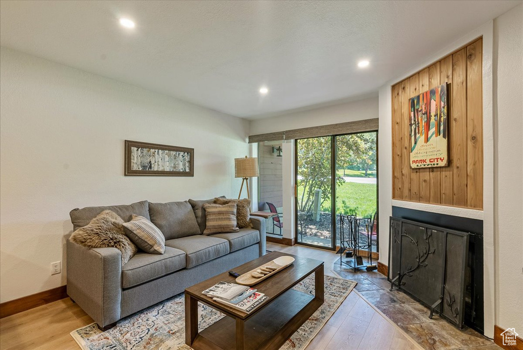 Living room featuring a fireplace with flush hearth, baseboards, recessed lighting, and wood-type flooring