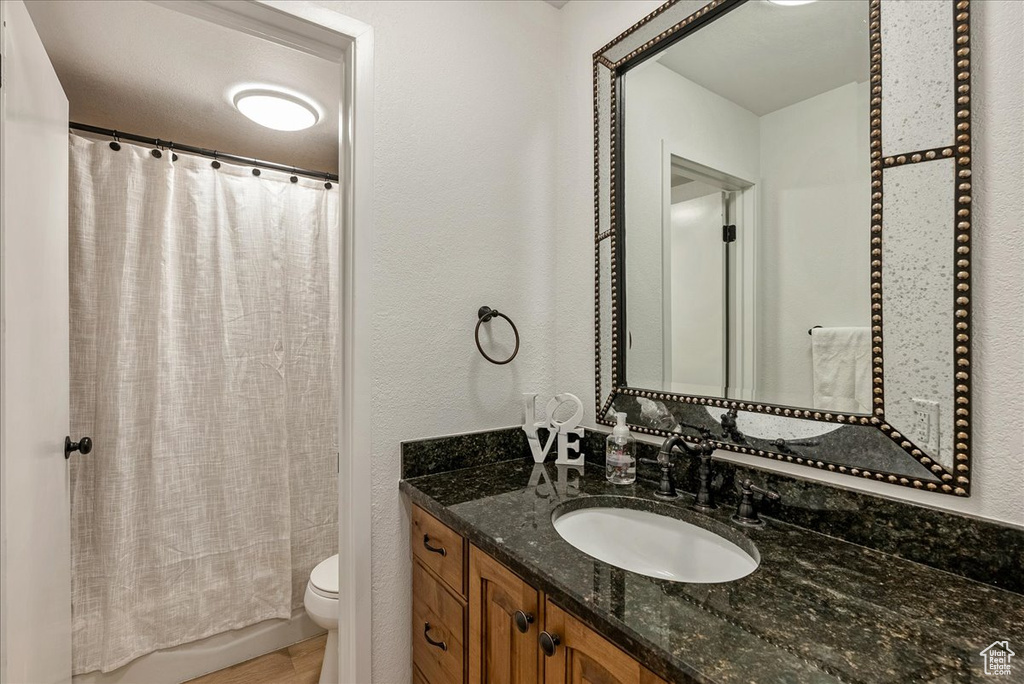 Full bathroom featuring a textured wall, toilet, vanity, and wood finished floors