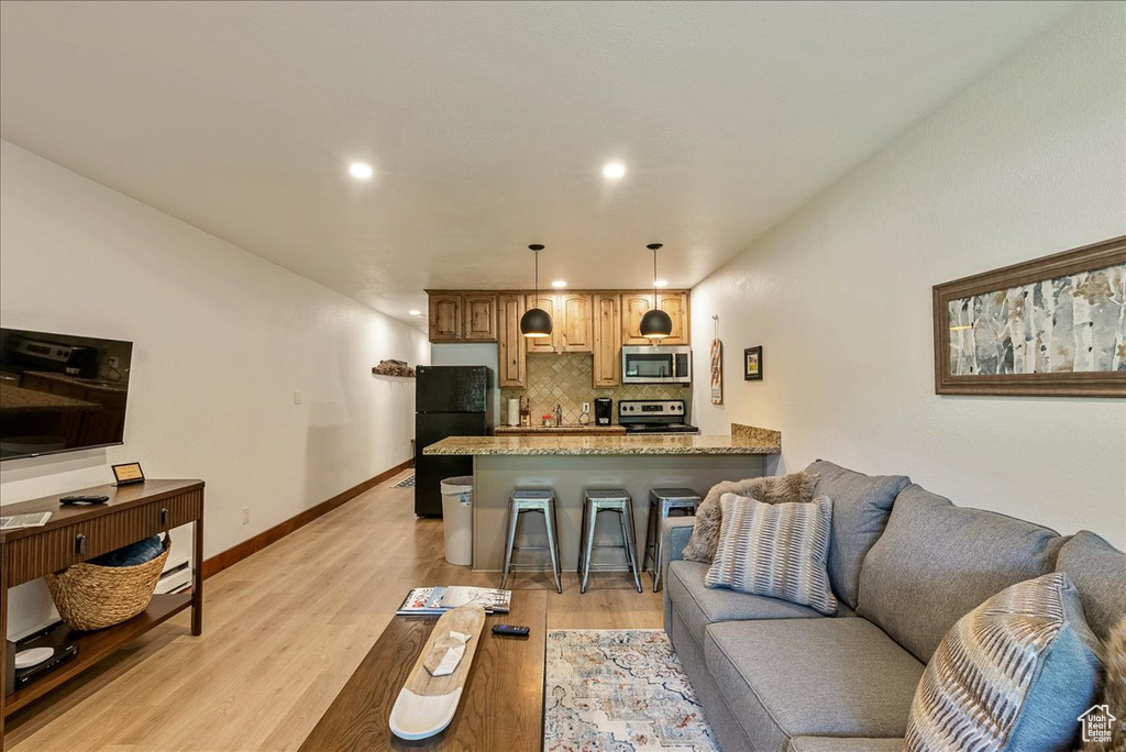 Living area with light wood finished floors, baseboards, and recessed lighting