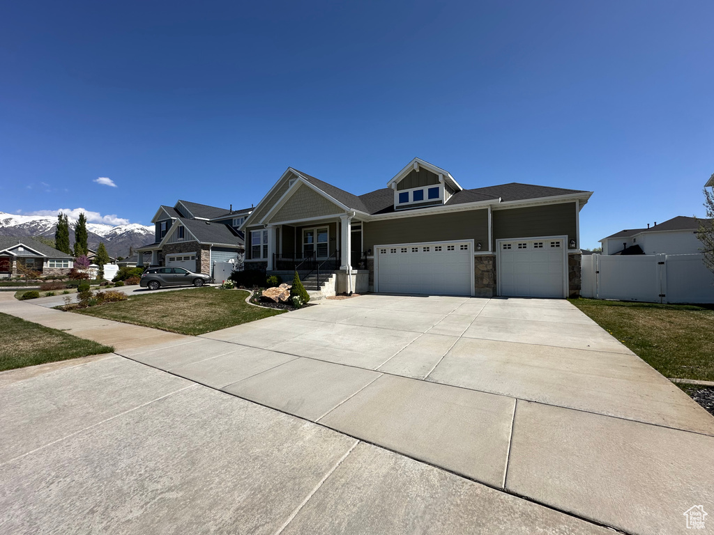Craftsman-style house with a garage, concrete driveway, fence, a mountain view, and a front yard