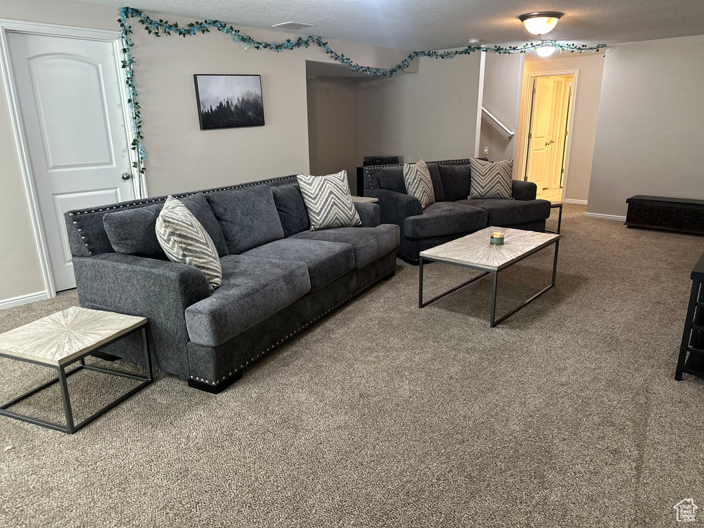 Living area with visible vents, baseboards, carpet flooring, and stairs