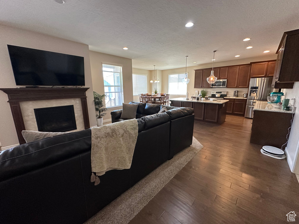 Living area featuring dark wood-type flooring, a textured ceiling, recessed lighting, and a fireplace