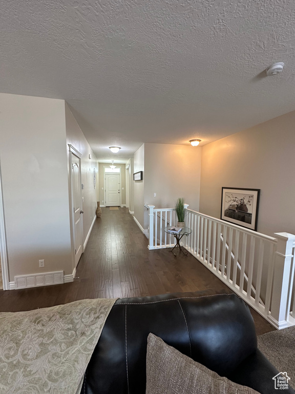 Corridor with visible vents, an upstairs landing, wood-type flooring, baseboards, and a textured ceiling