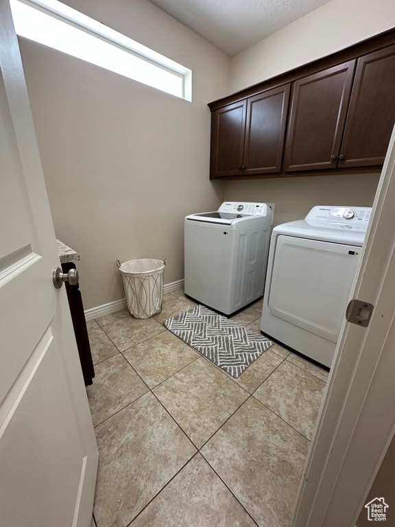 Washroom featuring cabinet space, baseboards, light tile patterned floors, and separate washer and dryer