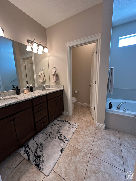 Full bath with double vanity, a garden tub, toilet, and a sink