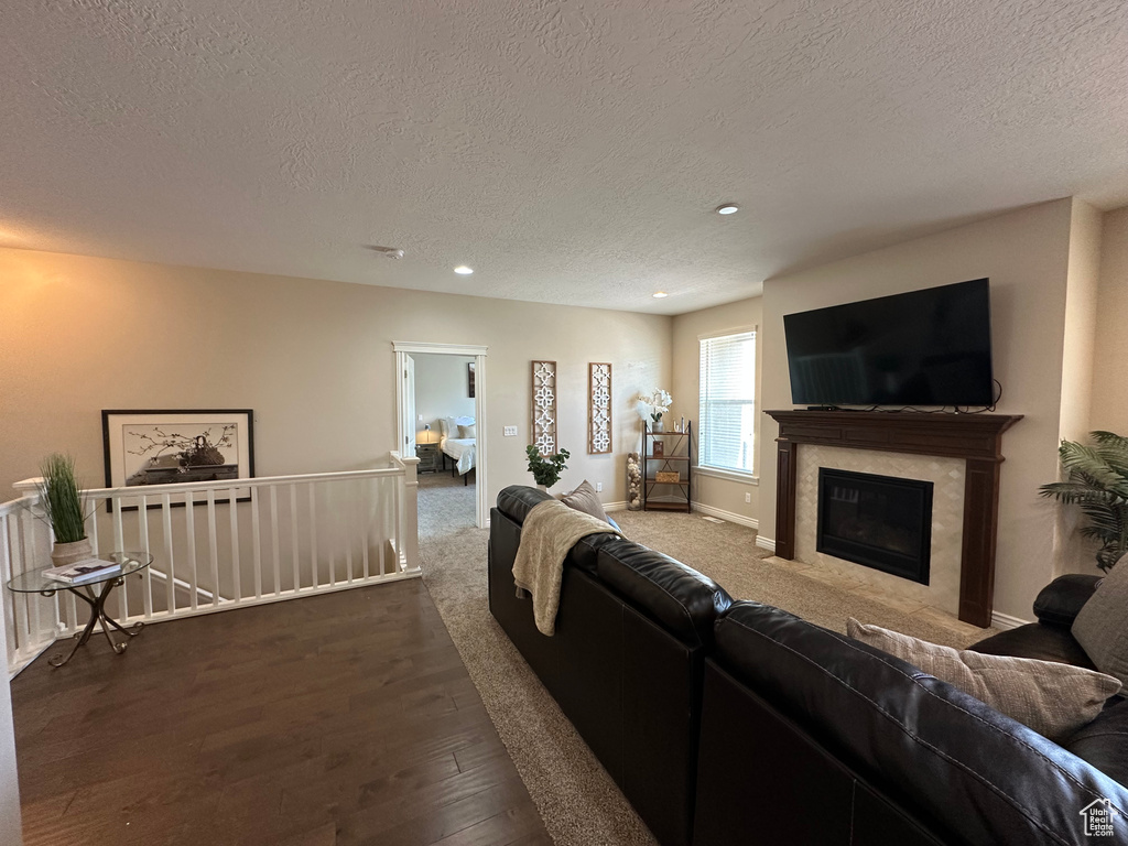 Living room featuring a textured ceiling, baseboards, recessed lighting, wood finished floors, and a fireplace