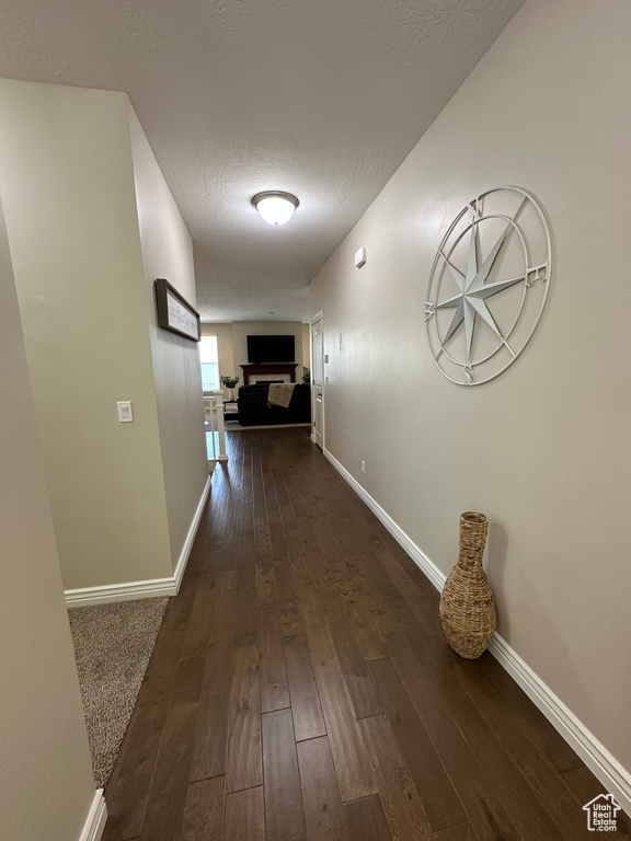 Hall with baseboards, a textured ceiling, and dark wood finished floors