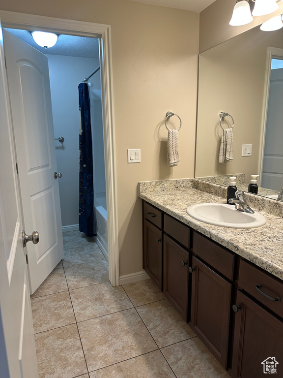 Bathroom featuring shower / bath combo, baseboards, tile patterned floors, and vanity