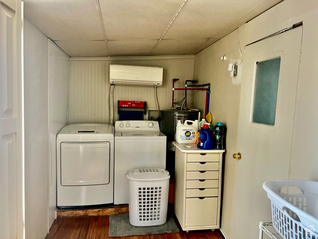 Laundry room featuring dark wood-type flooring, washer and clothes dryer, laundry area, and a wall unit AC