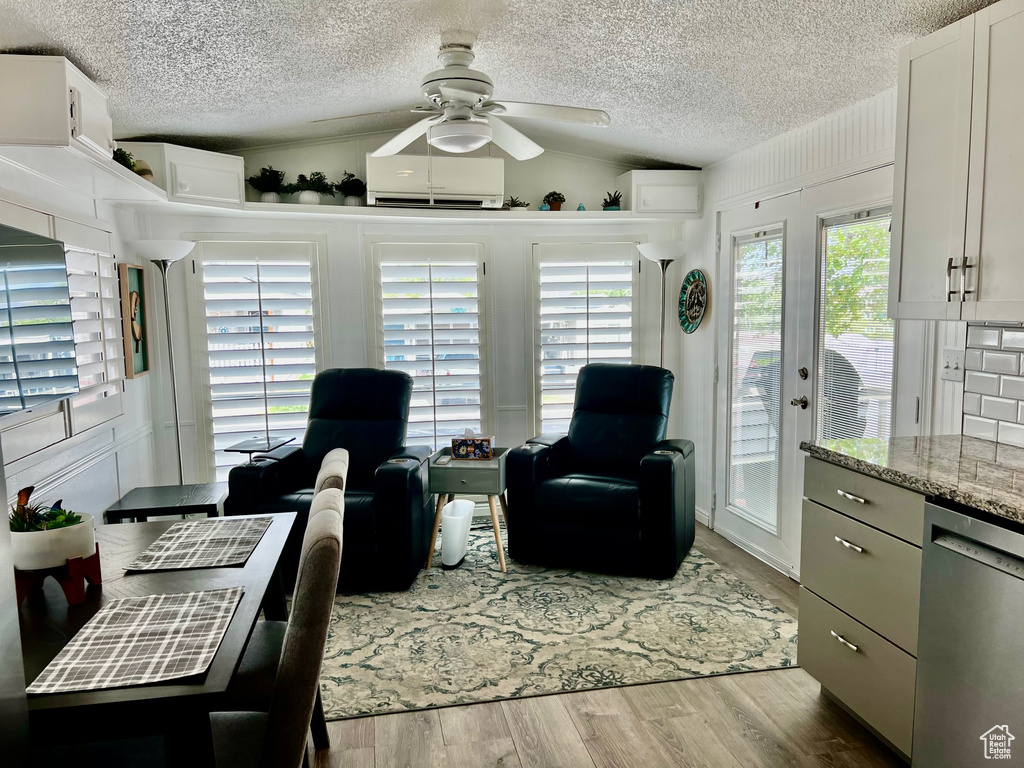 Living area featuring wood finished floors, a textured ceiling, ceiling fan, and a wall mounted air conditioner