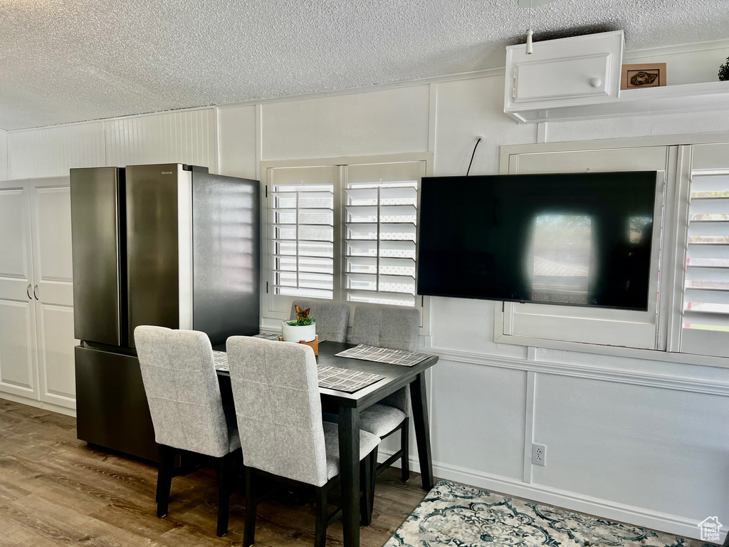 Dining room featuring wood finished floors, a textured ceiling, and a decorative wall