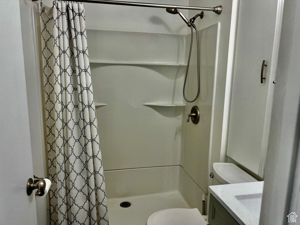 Bathroom with toilet, vanity, and a stall shower