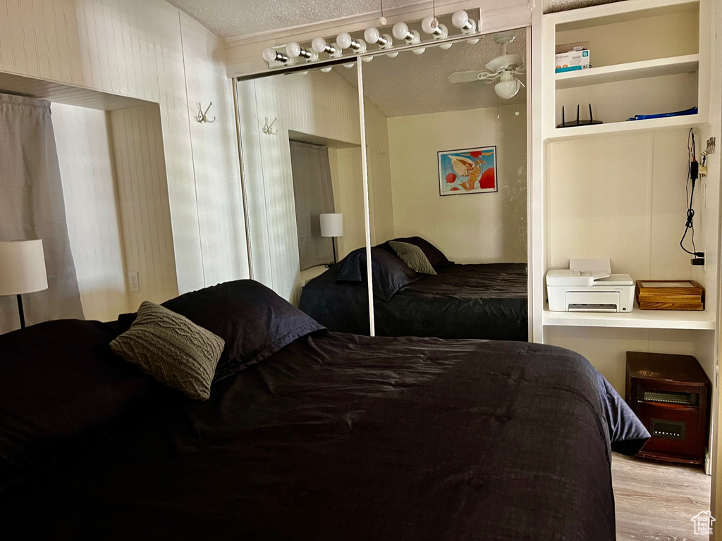 Bedroom featuring wood finished floors, a textured ceiling, and a closet