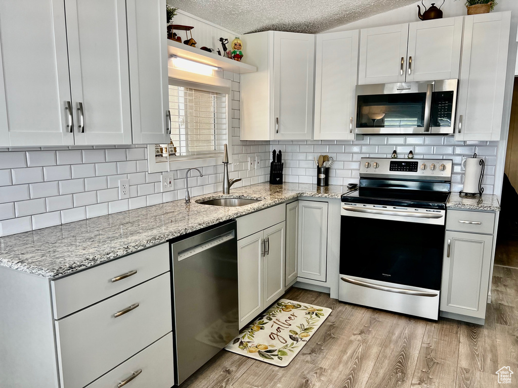 Kitchen featuring decorative backsplash, stainless steel appliances, a sink, and a textured ceiling