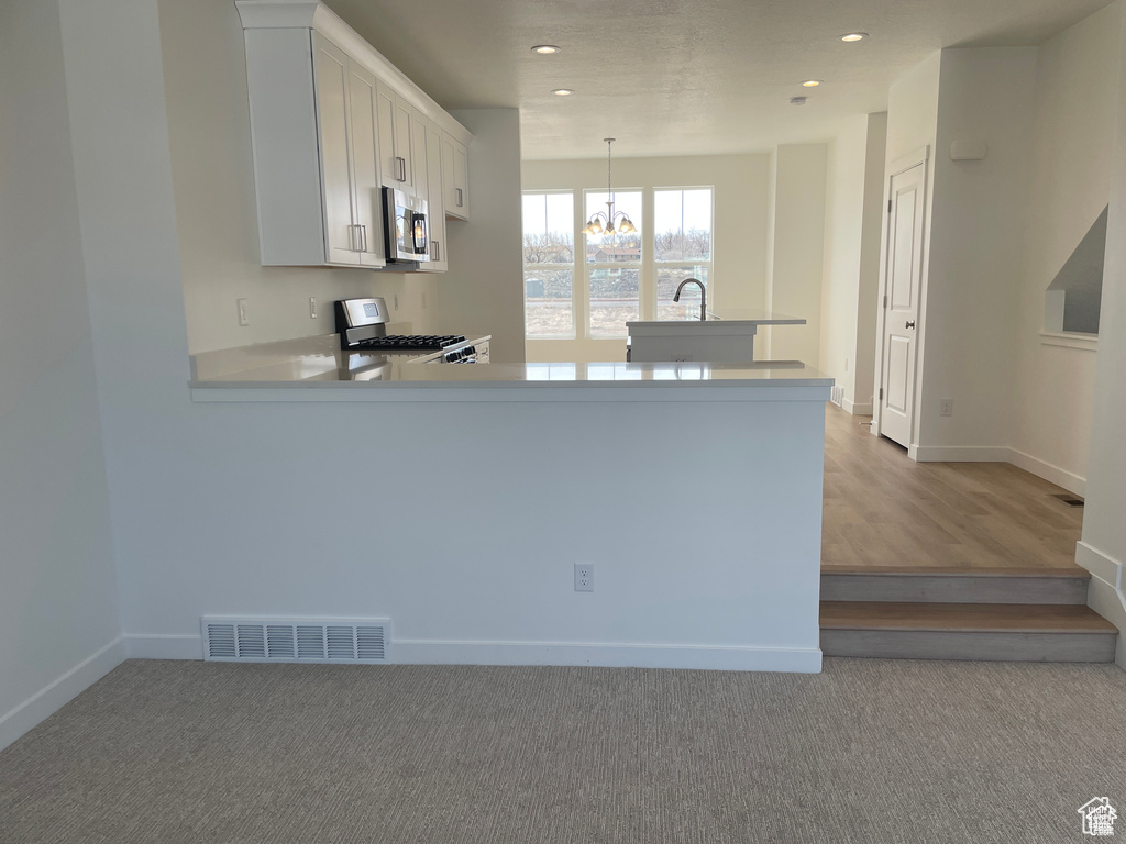 Kitchen featuring stainless steel appliances, visible vents, recessed lighting, a notable chandelier, and light countertops