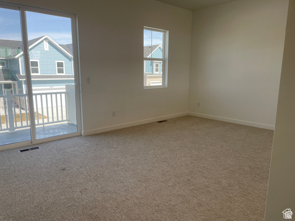 Carpeted empty room featuring baseboards and visible vents