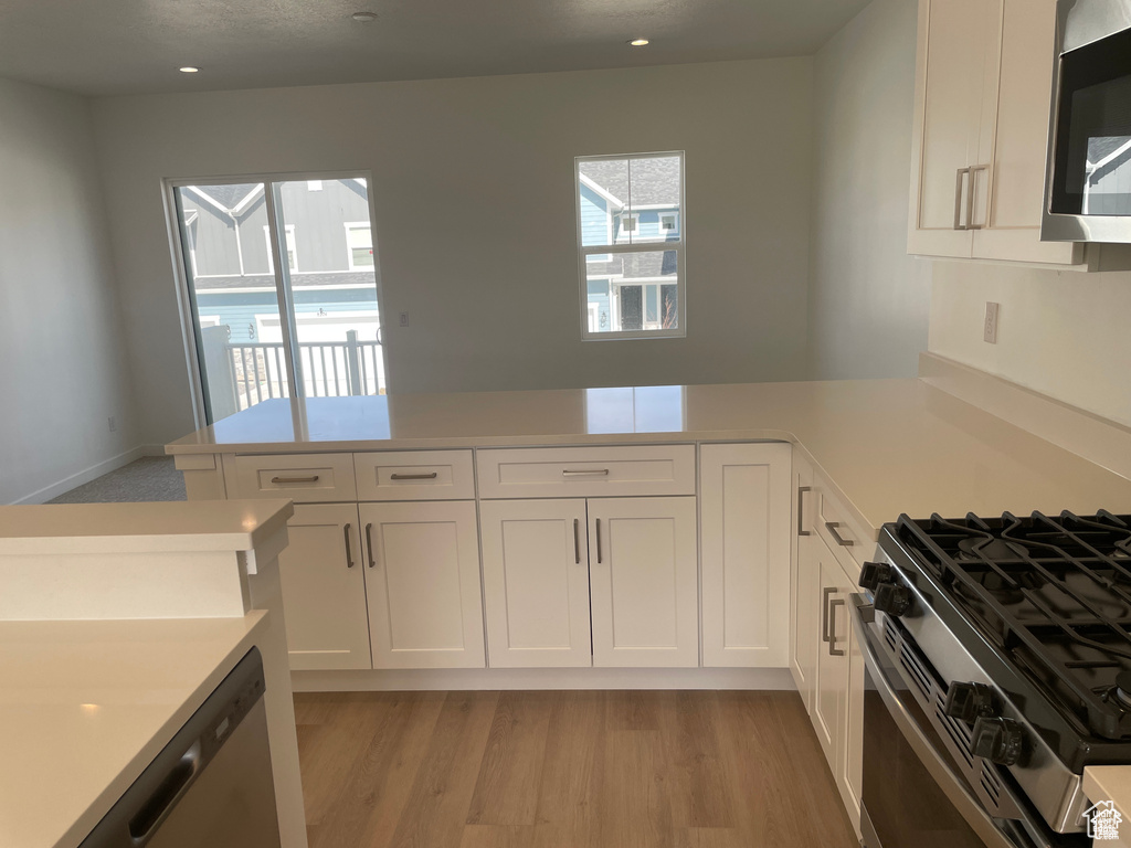 Kitchen with white cabinets, stainless steel appliances, light countertops, and a peninsula