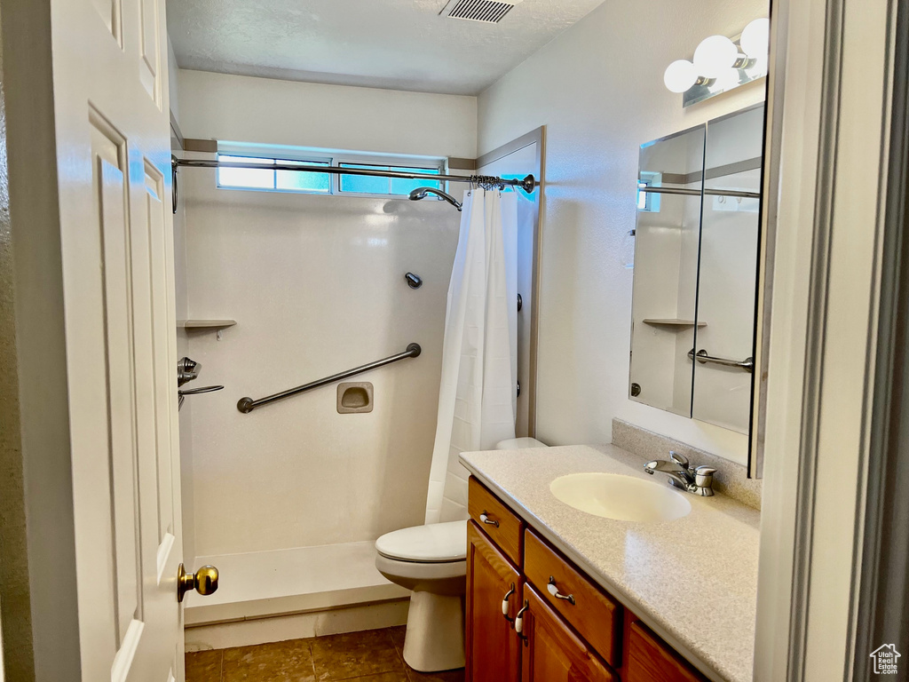 Bathroom featuring curtained shower, vanity, and tile patterned floors