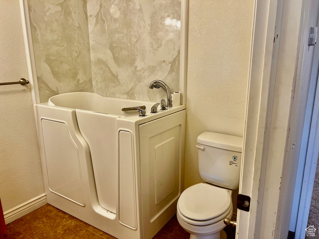 Full bath with toilet, a textured wall, and tile patterned flooring