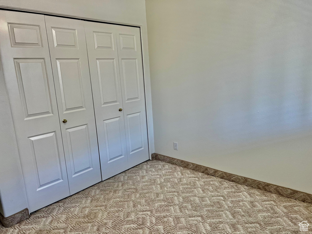 Unfurnished bedroom with light colored carpet and a closet