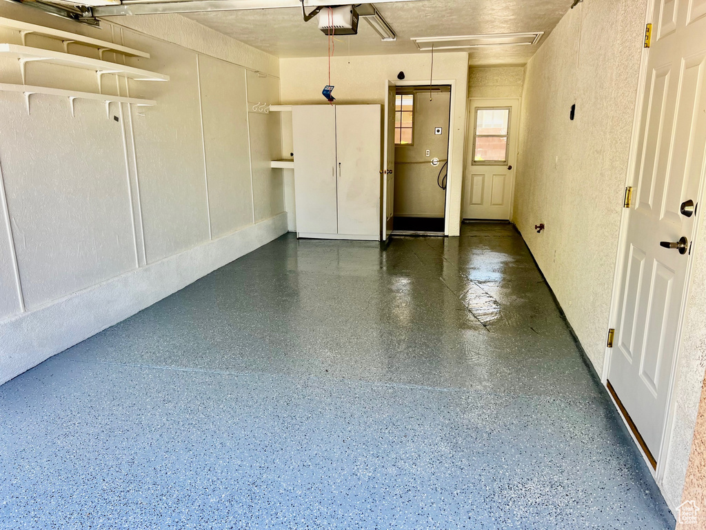 Garage featuring a garage door opener and a textured wall