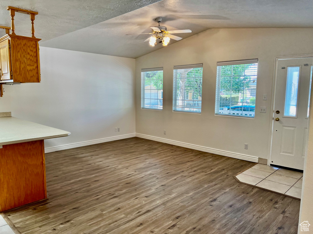 Unfurnished dining area featuring wood finished floors, a ceiling fan, and vaulted ceiling