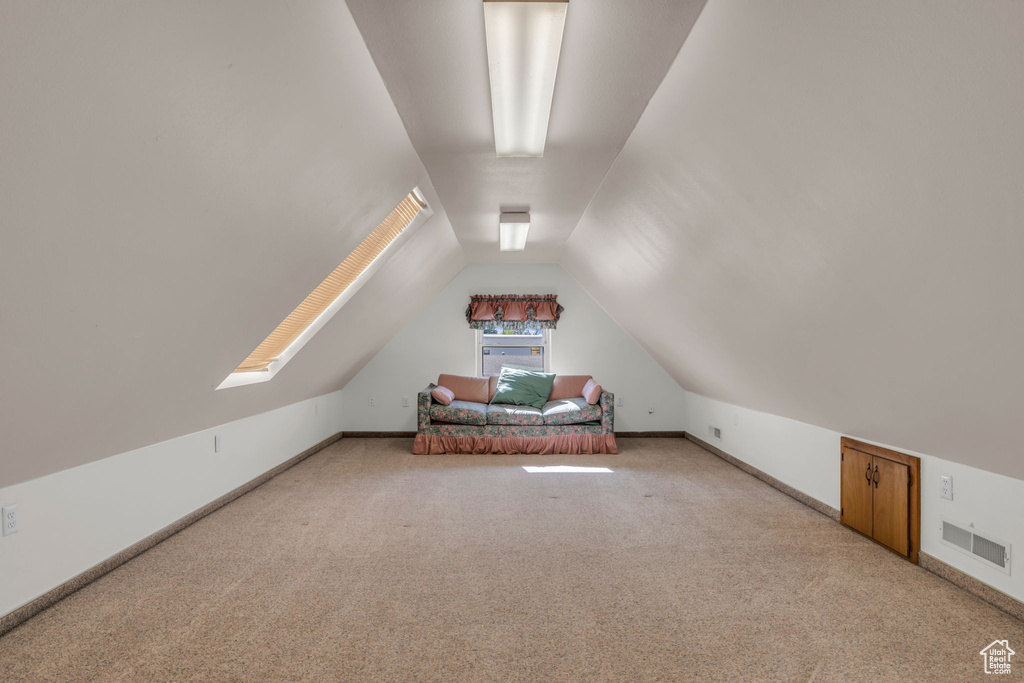 Bonus room featuring lofted ceiling, visible vents, baseboards, and light carpet