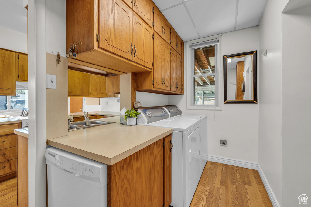 Laundry room with light wood finished floors, laundry area, a sink, a wealth of natural light, and baseboards