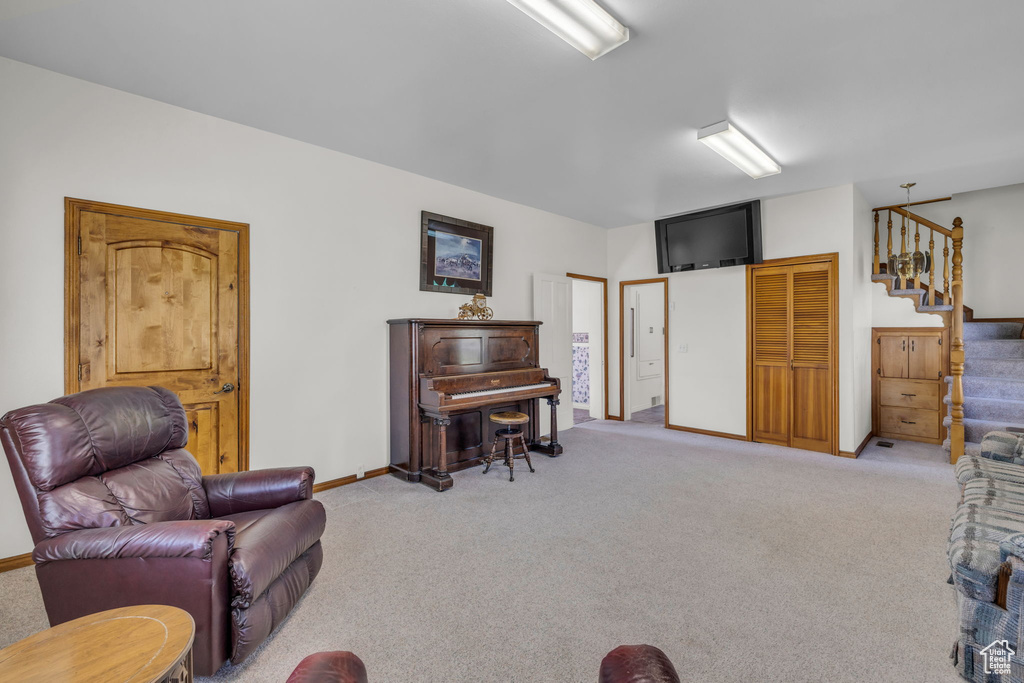 Living room featuring light carpet, baseboards, and stairway