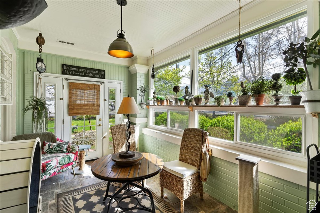 Sunroom with stone tile flooring, visible vents, and plenty of natural light