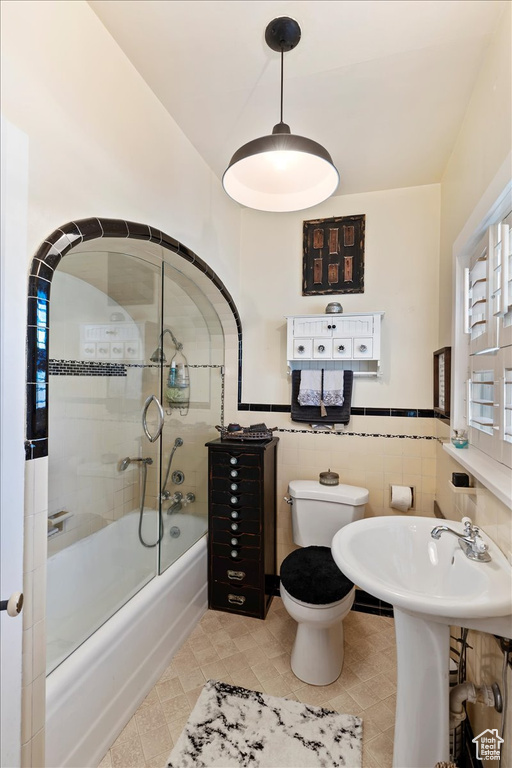 Full bath featuring toilet, a wainscoted wall, and a sink