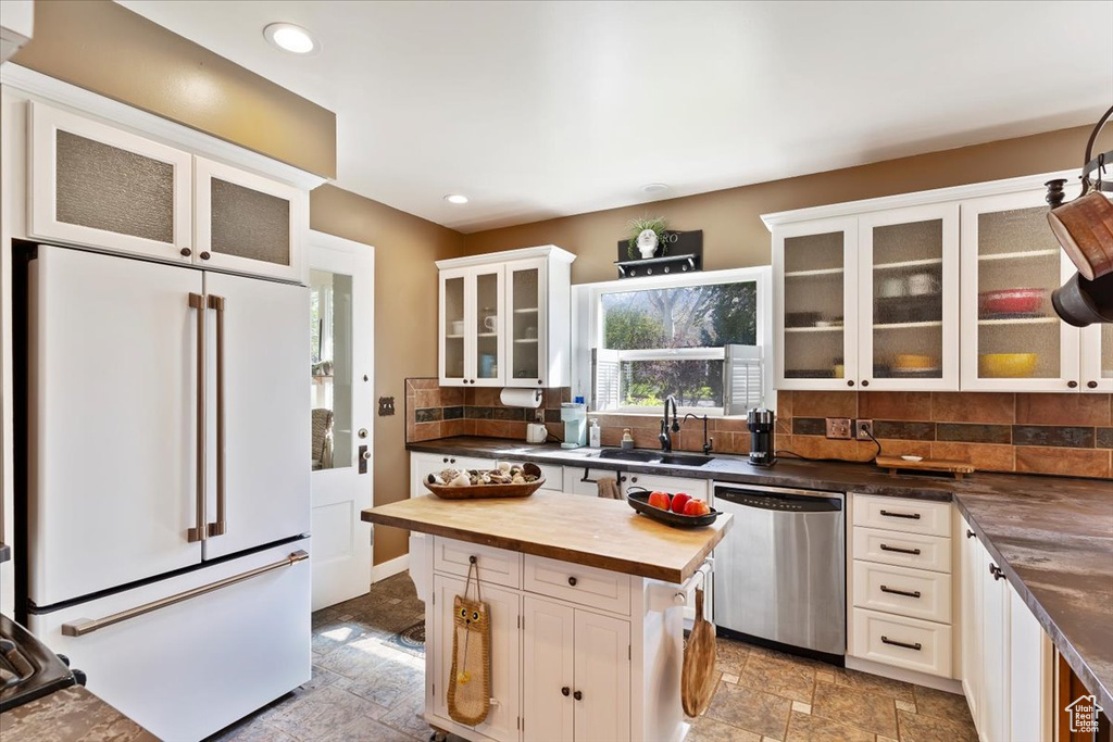 Kitchen featuring high end white refrigerator, stone finish flooring, stainless steel dishwasher, and butcher block countertops