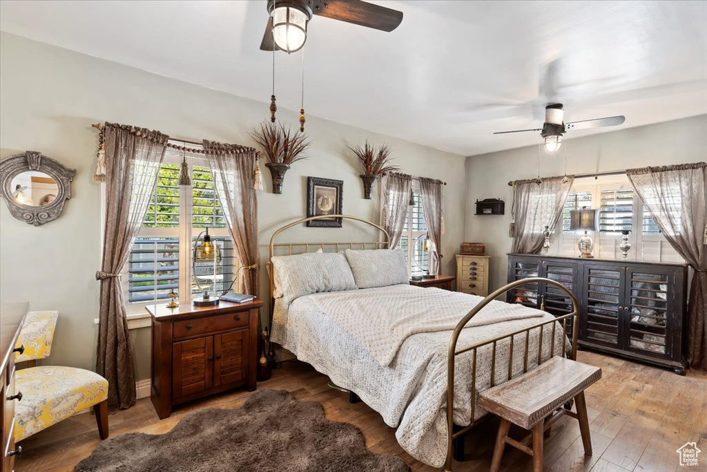 Bedroom with a ceiling fan, wood finished floors, and multiple windows
