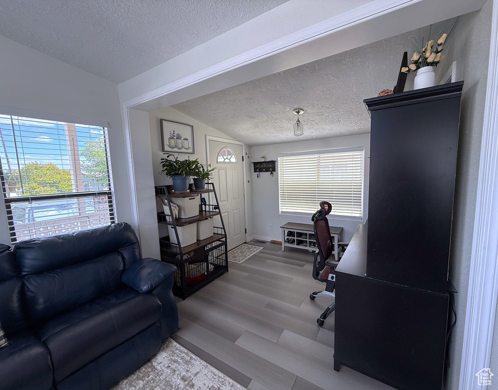 Office area featuring a textured ceiling, wood finished floors, vaulted ceiling, and baseboards