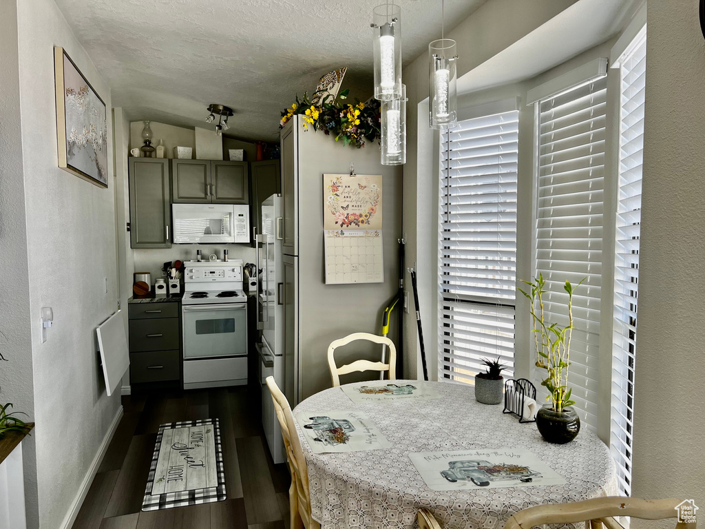 Kitchen featuring dark wood finished floors, lofted ceiling, white appliances, and plenty of natural light