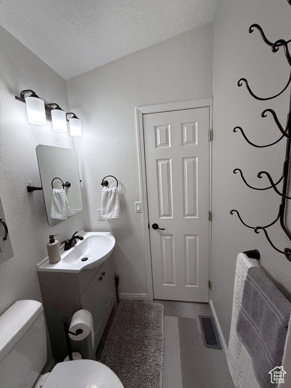 Bathroom with toilet, vanity, a textured ceiling, and baseboards