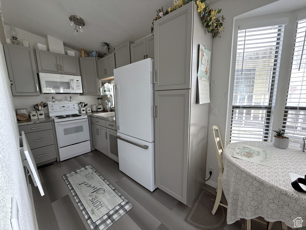 Kitchen featuring white appliances, vaulted ceiling, light countertops, gray cabinetry, and light wood-style flooring