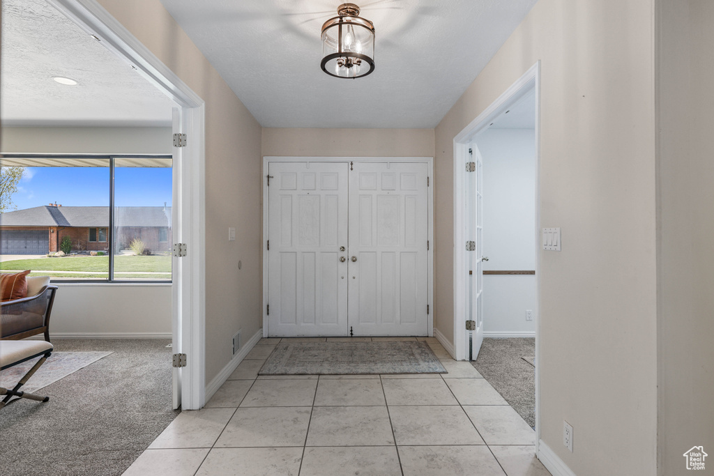Entryway featuring light colored carpet, baseboards, and light tile patterned flooring