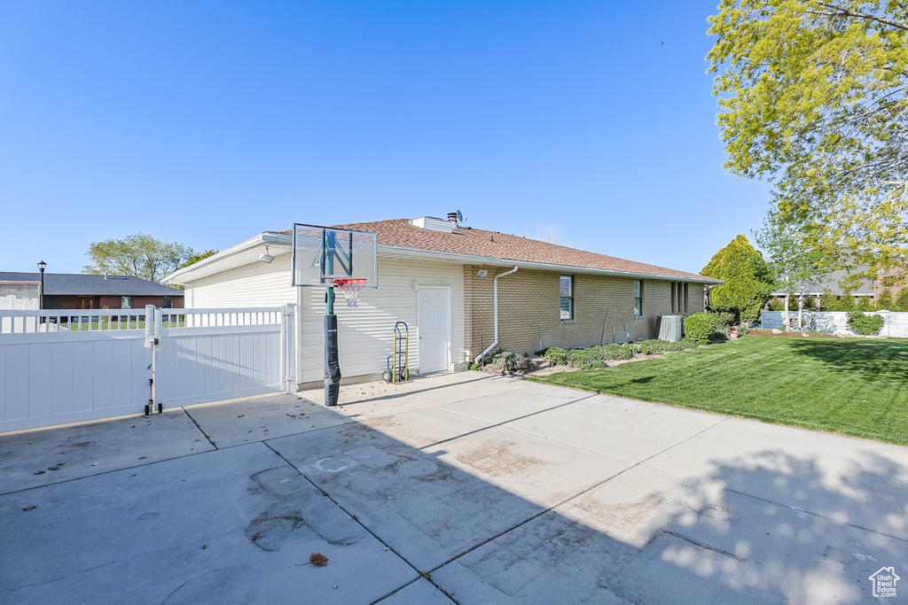 View of home\\\\\\\'s exterior with a gate, brick siding, fence, and a lawn