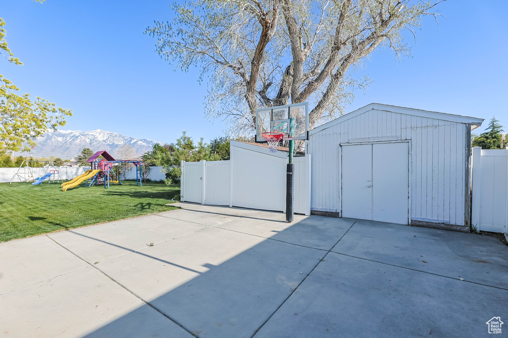Exterior space featuring a shed, a playground, fence, and a mountain view