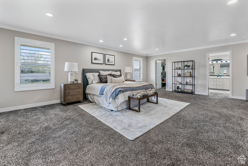 Carpeted bedroom featuring baseboards, recessed lighting, a walk in closet, and crown molding