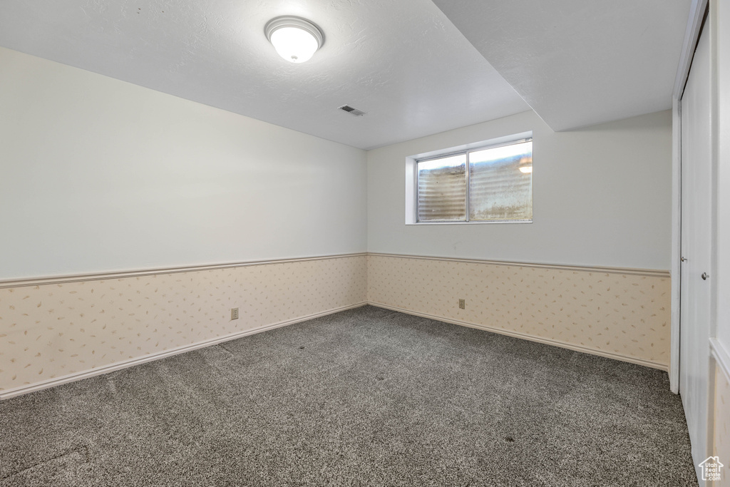 Unfurnished bedroom featuring wainscoting, carpet floors, visible vents, and wallpapered walls