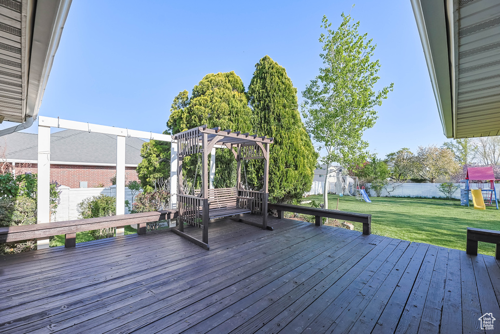 Wooden terrace featuring a yard, a fenced backyard, and a playground