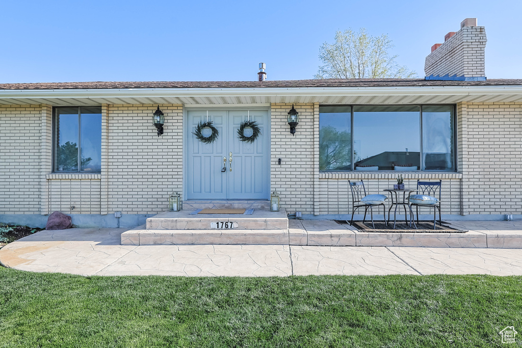 Entrance to property with a chimney and brick siding