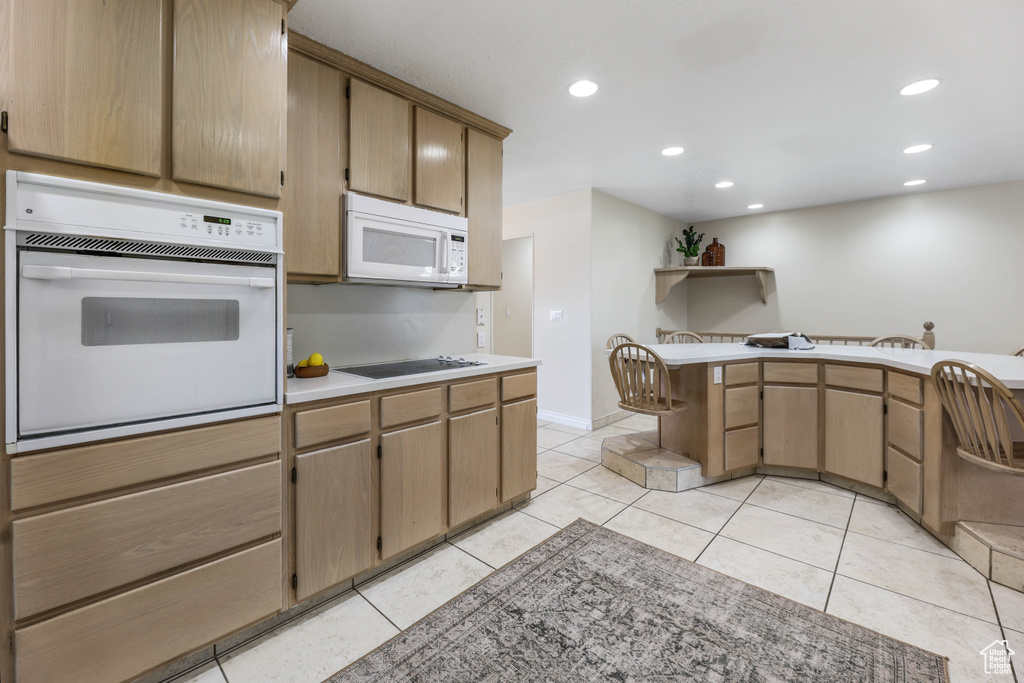 Kitchen with light countertops, white appliances, recessed lighting, and light tile patterned flooring